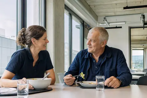 Zwei erfahrene Mitarbeitende der Gebäudetechnik beim gemeinsamen Mittagessen